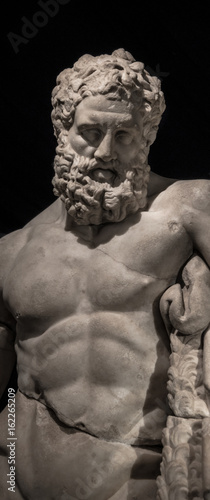 Statue of powerful Hercules, closeup, isolated at black background