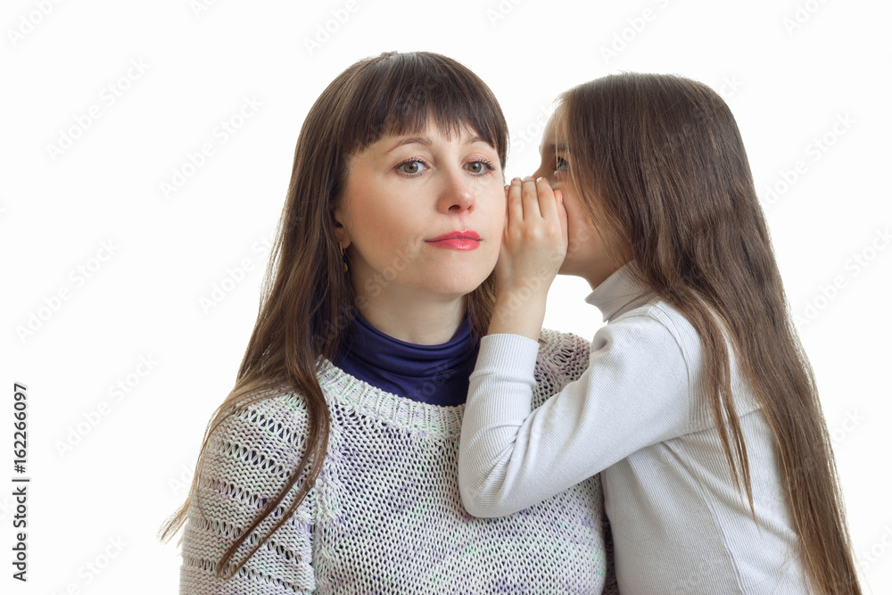 the little girl says something to her mother's ear close-up the little girl says something to her mother's ear close-up