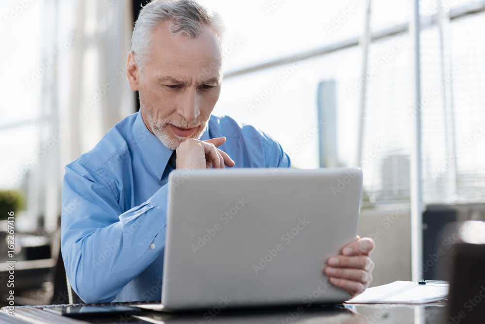 Attentive man looking at his new laptop Attentive man looking at his new laptop