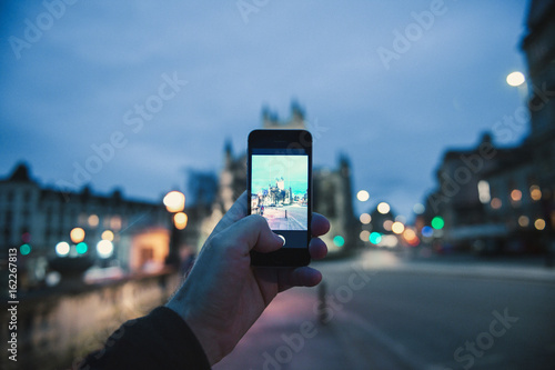 Personal Perspective pov of man taking photograph with the mobile phone smartphone of the illuminated cathedral Bath Abbey in Bath, United Kingdom 