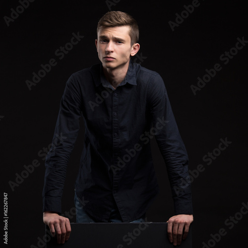 Young confident man portrait of a confident businessman showing presentation, pointing placard black background. Ideal for banners, registration forms, presentation, landings, presenting concept.