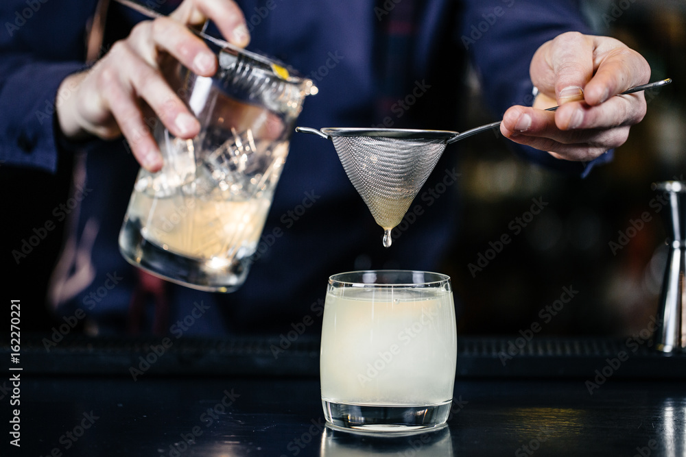 Bartender is making cocktail at bar.