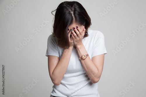 Sad young Asian woman cry with palm to face. © halfbottle