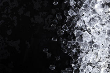 Crushed ice background. Pieces of crushed ice cubes on black background. Copy space, top view