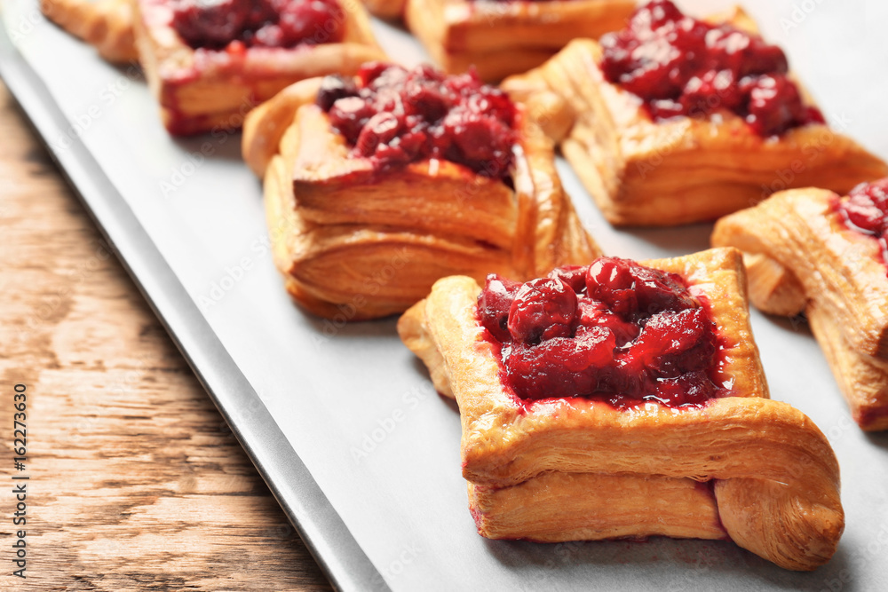 Tray with delicious puff pastries and cherry on wooden table Tray with delicious puff pastries and cherry on wooden table