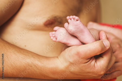 newborn baby feet on the fathers hands 