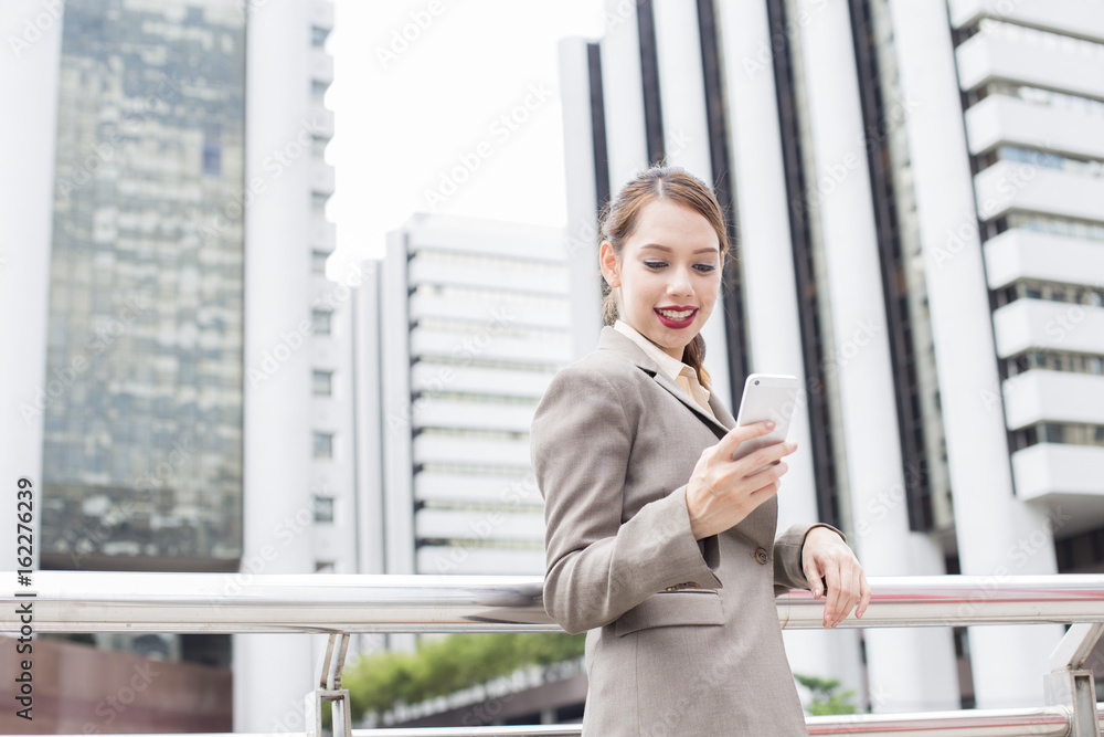 Young asian businesswoman using smartphone for touching with attractive smiling at city. woman resting at city concept, 20-30 year old. Young asian businesswoman using smartphone for touching with attractive smiling at city. woman resting at city concept, 20-30 year old.