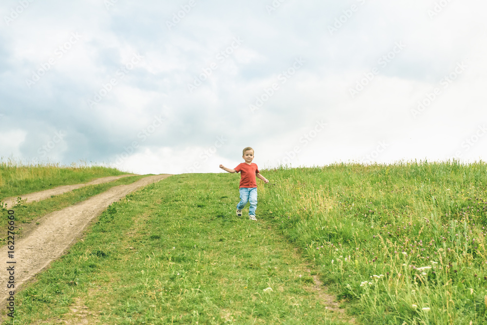 Little boy running across the field on the lawn on a summer day Little boy running across the field on the lawn on a summer day