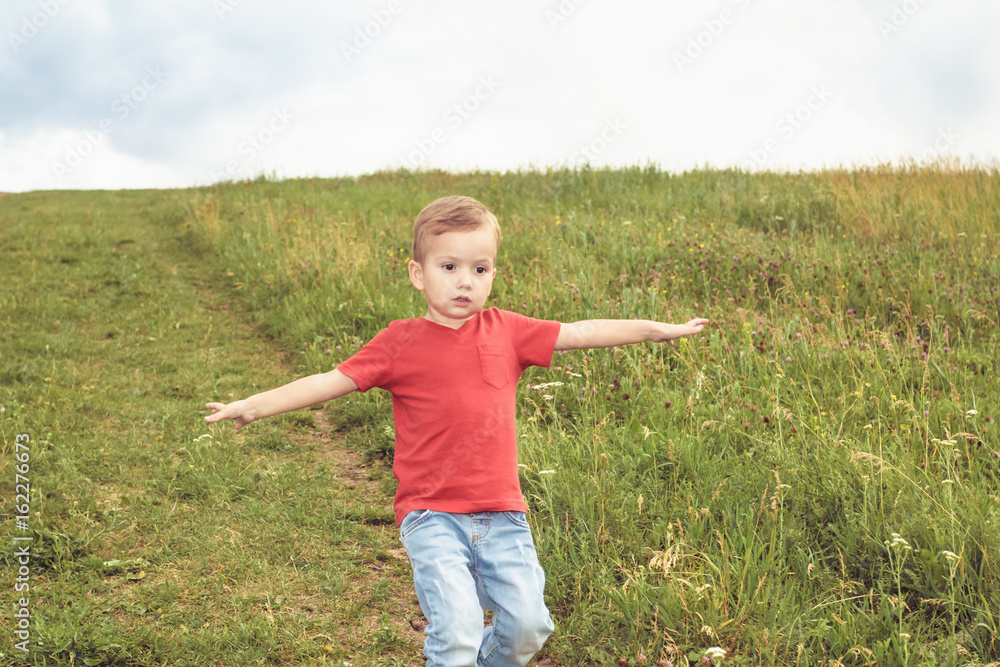 Little boy running across the field on the lawn on a summer day Little boy running across the field on the lawn on a summer day