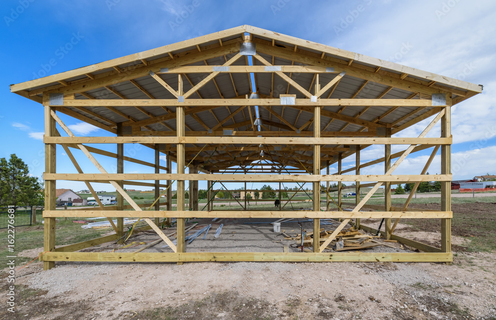 Garage construction in suburbia, USA. Wood, wooden roof truss system. Gray corrugated metal cladding panel on the roof Garage construction in suburbia, USA. Wood, wooden roof truss system. Gray corrugated metal cladding panel on the roof