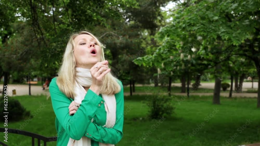 Girl with dandelion in the park. A woman is blowing a dandelion.
