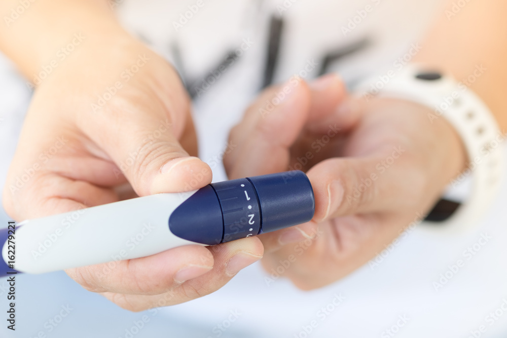 Close up of woman hands using lancet on finger to check blood sugar level by Glucose meter using as Medicine, diabetes, glycemia, health care and people concept. Close up of woman hands using lancet on finger to check blood sugar level by Glucose meter using as Medicine, diabetes, glycemia, health care and people concept.