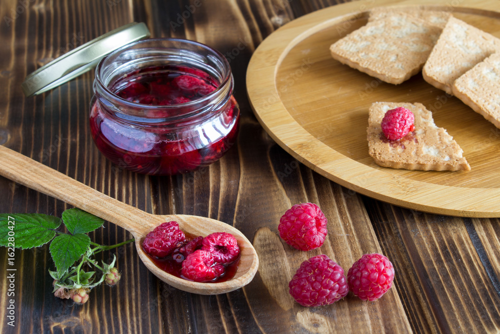 Raspberry jam and cookies on the wooden background