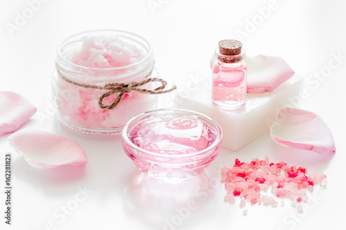 spa set with rose flowers extract and cosmetic for body on white desk background