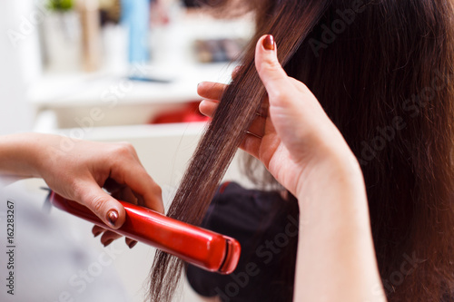Stylist align the customer's hair with straightener