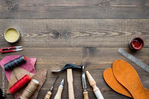 Set of cobbler tools on brown wooden desk background top view copyspace