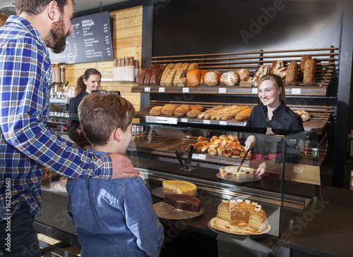 Father and son buying organic cake in a bakery