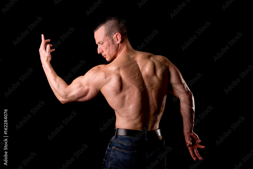 fit muscular man posing isolated on a dark background fit muscular man posing isolated on a dark background