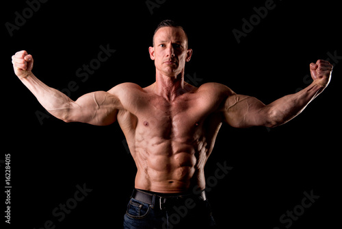 fit muscular man posing isolated on a dark background