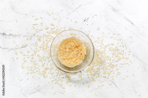 rice in bowl for paella on white desk background top view mock up