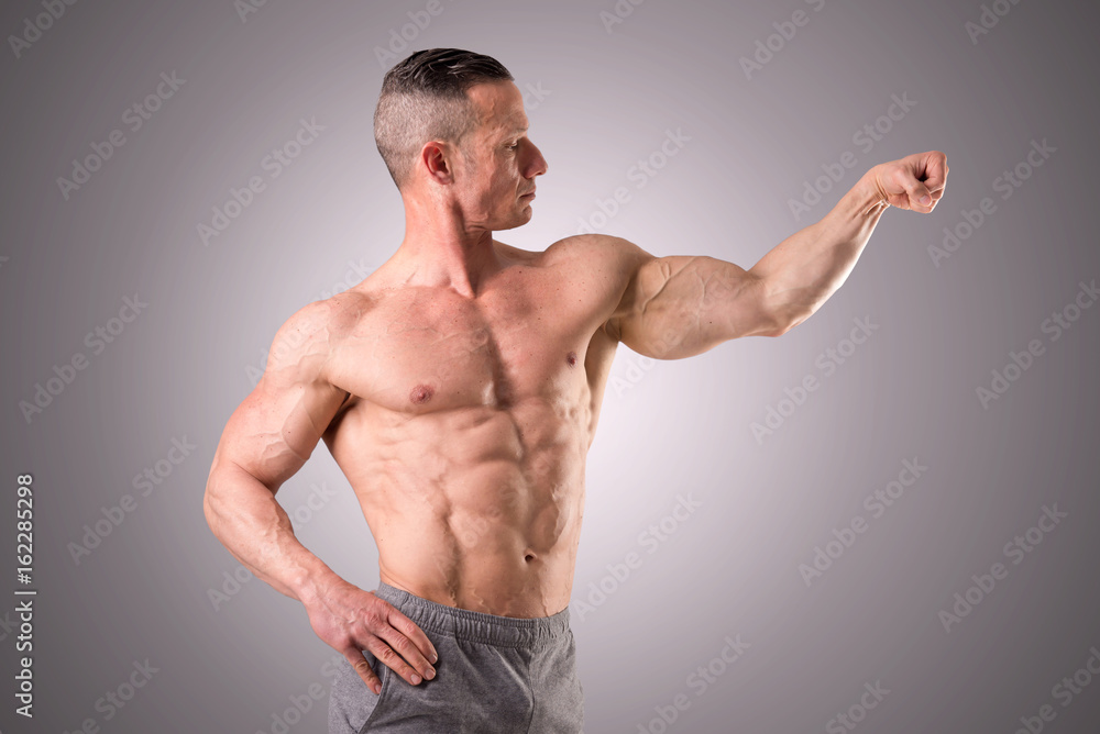 fit muscular man posing isolated on a grey background