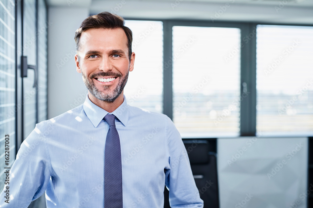 Fototapeta premium Middle-aged businessman smiling and looking straight at camera