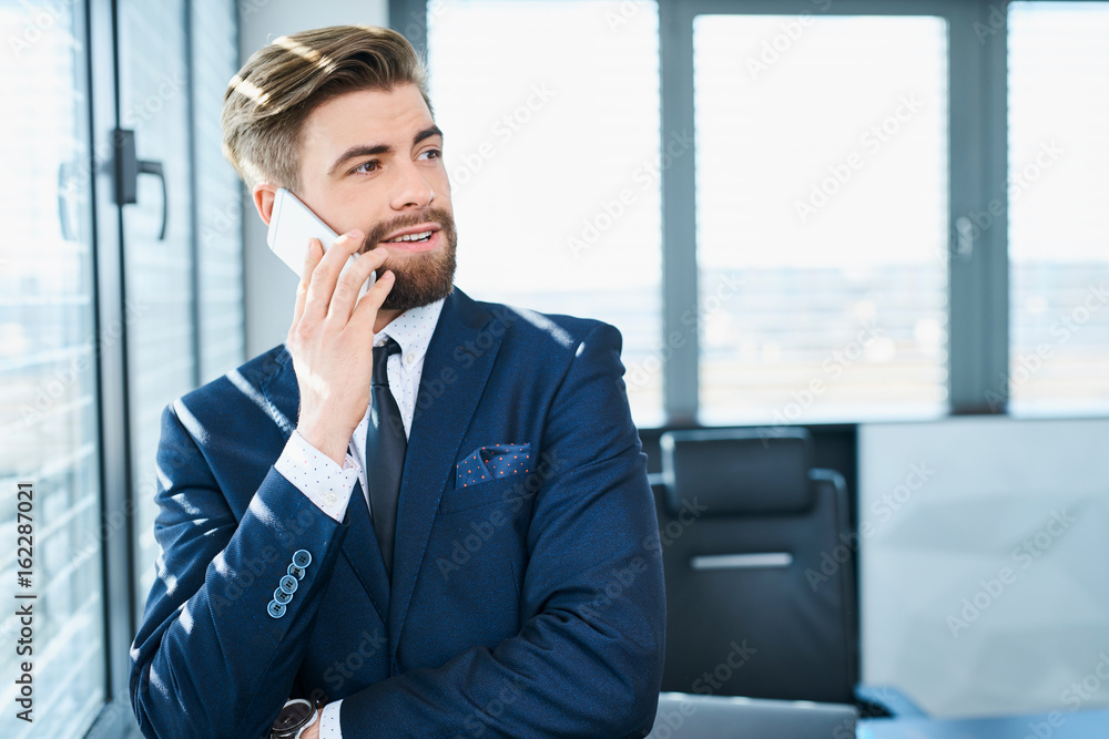 Young handsome manager talking on the phone while in office Young handsome manager talking on the phone while in office