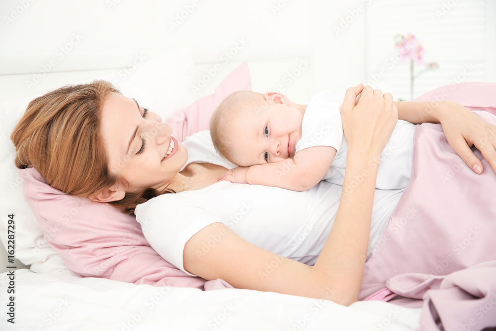 Happy young woman with cute baby lying on bed at home Happy young woman with cute baby lying on bed at home