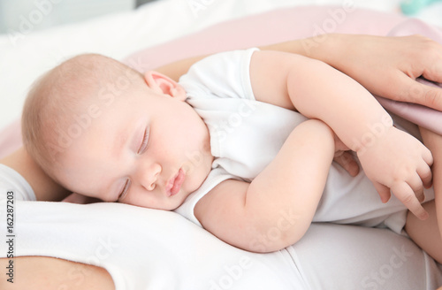 Young woman with cute sleeping baby at home, closeup