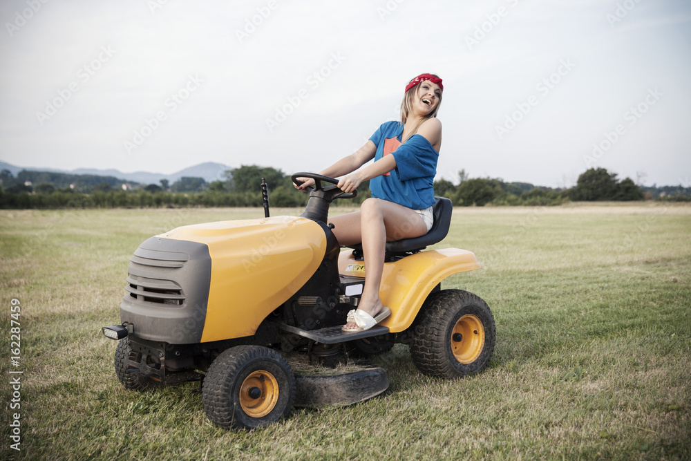Working girl driving a lawn mower Working girl driving a lawn mower