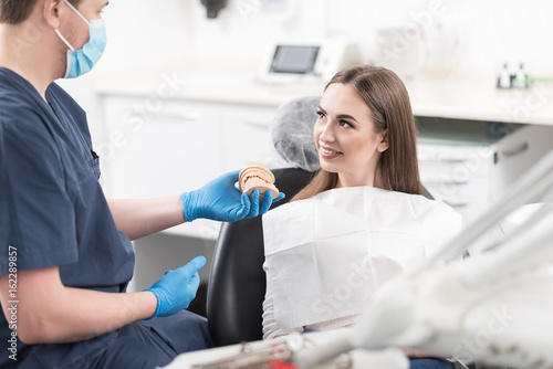 Dentist showing typodont to cheerful patient photo