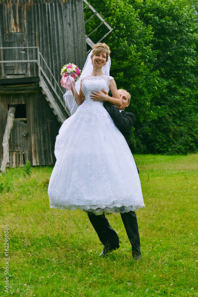 Fototapeta premium happy bride and groom jumping near the old mill on village