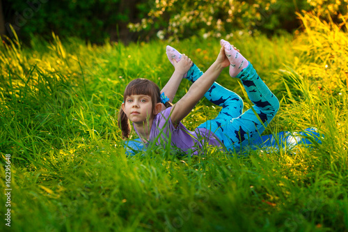 beautiful girl doing yoga outdoors On green grass photo