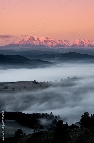 panorama over misty Spisz highland to snowy Tatra mountains in the morning, Poland landscape © tomeyk