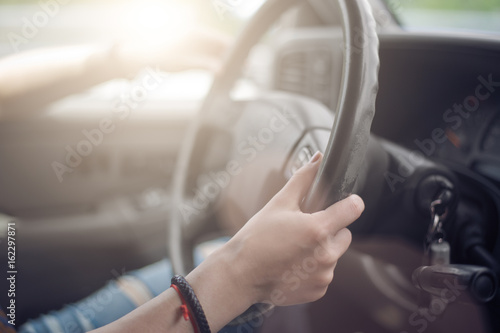 Women's hands hold the wheel of a car
