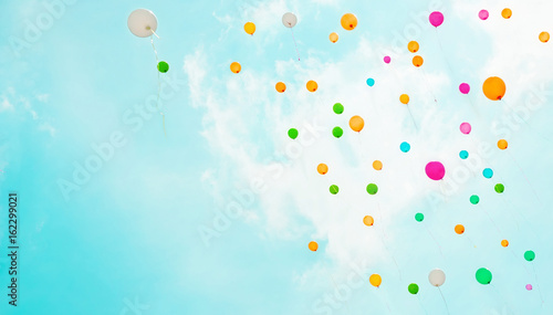 Background with multicolored flying balloons in blue sky