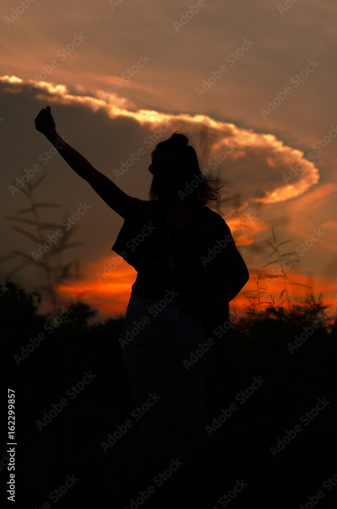 Silhouette girl on sunset background. Relax and happy. a young asian woman enjoying flowers and nature sunset