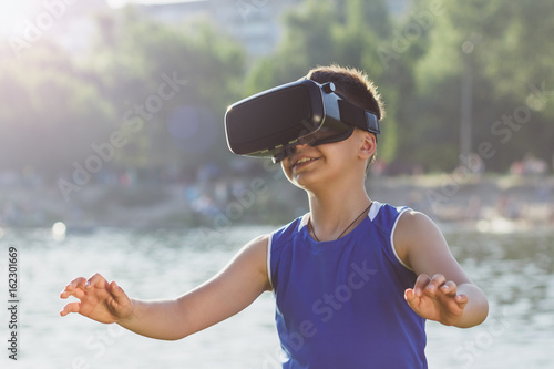 Boy plays game with virtual reality glasses outdoors