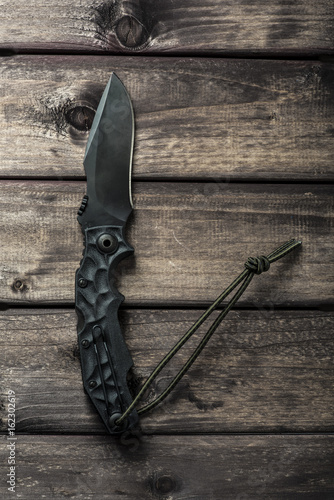 Hunting clasp-knife on wooden backdrop