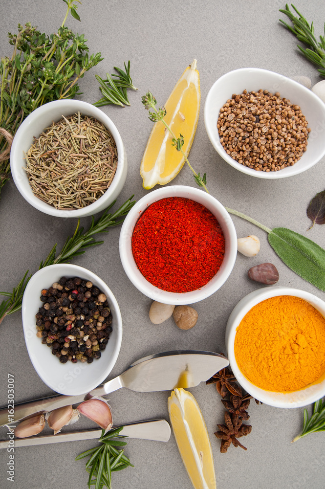 Various dried and spices and fresh seasonings on a gray table.. Various dried and spices and fresh seasonings on a gray table..