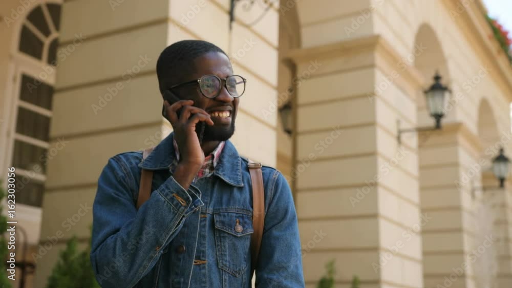 Portrait of african american man in casual clothes in city talking on smart phone and smiling. Portrait of african american man in casual clothes in city talking on smart phone and smiling.