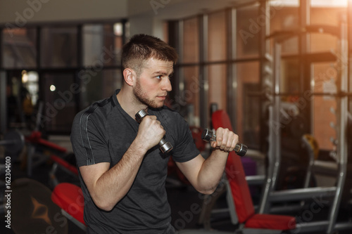 Young muscular man boxer, boxing gloves. Young man in the gym, boxing with dumbbells. © viktoryabov