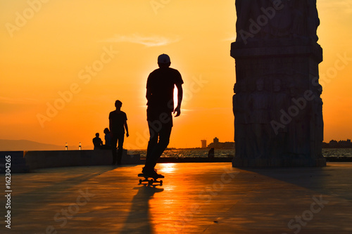 Obraz na plátně Young man skateboarder skateboarding at sunset, silhouette.