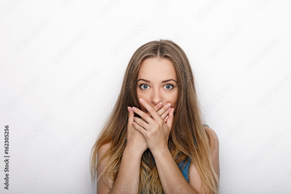 Headshot of young adorable blonde woman covers her mouth on white background Headshot of young adorable blonde woman covers her mouth on white background