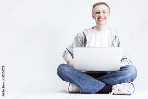 Modern Youth Lifestyle Ideas and Concepts. Smiling Handosme Caucasian Man with Laptopp Chatting. Posing Against White Background. photo