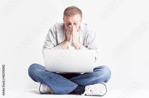 Portrait of Extremely Surprised Caucasian Man with Laptopp While Chatting. Posing Against White Background.Horizontal Image Composition. photo