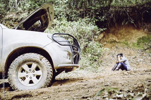 Stressed woman waiting for roadside assistance after her car breaks down on dirt road in forest © doidam10