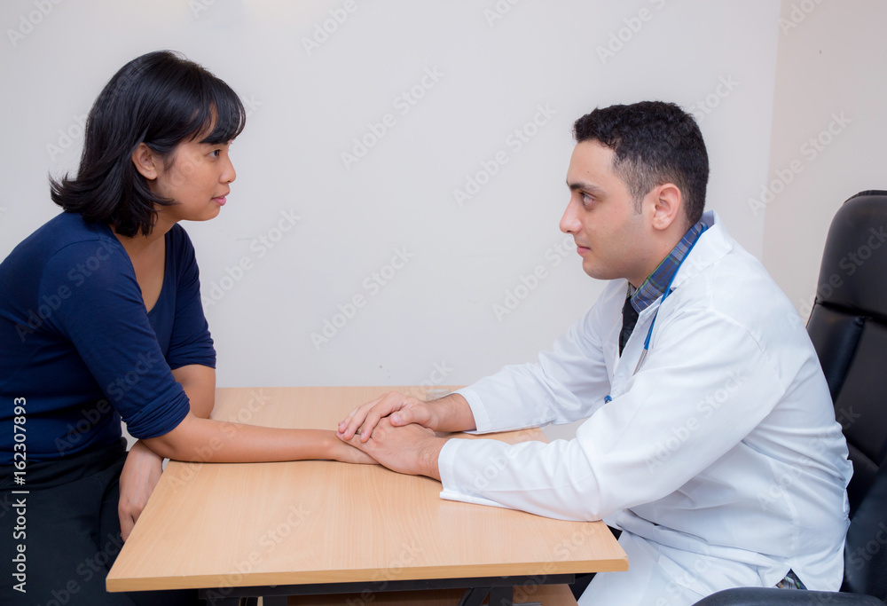 Friendly male doctor hand holding patient hand sitting at the desk for encouragement - empathy - cheering and support while medical examination. Friendly male doctor hand holding patient hand sitting at the desk for encouragement - empathy - cheering and support while medical examination.
