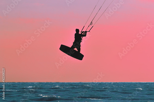 Silhouette of kitesurfer on sunset background