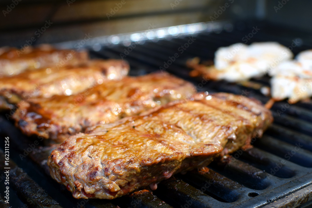 Juicy beef sirloin steaks on barbecue grill. Focus on foreground.
